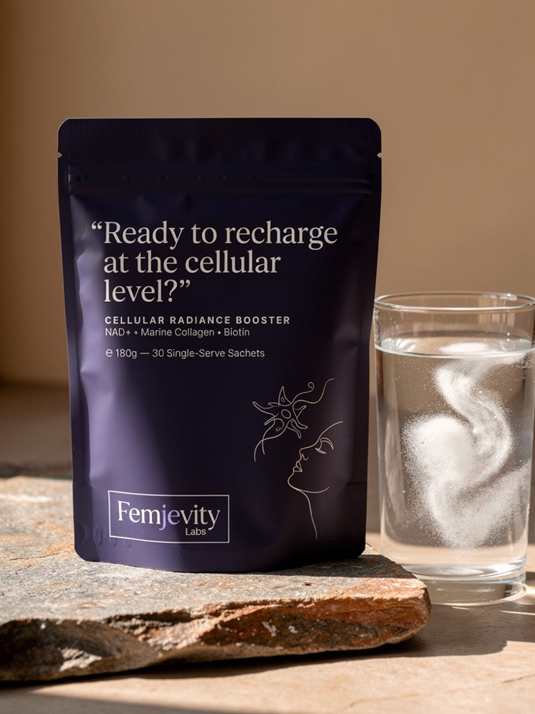 The sealed Femjevity Labs pouch beside a glass of water with a white swirl of dissolved powder, warm daylight.